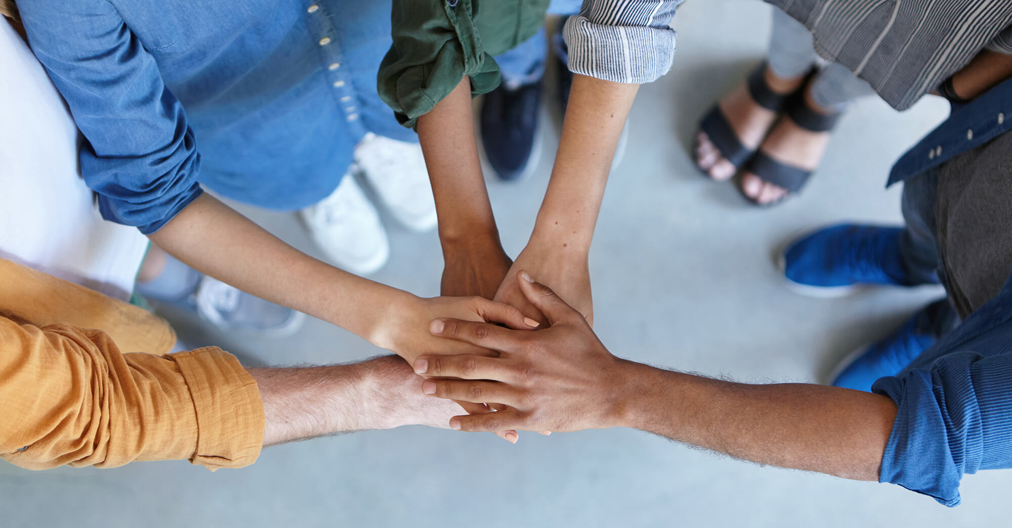 Daniela Burns, Coach in Salzburg, steht mit verschränkten Armen vor einer hellen Wand und lächelt in die Kamera.